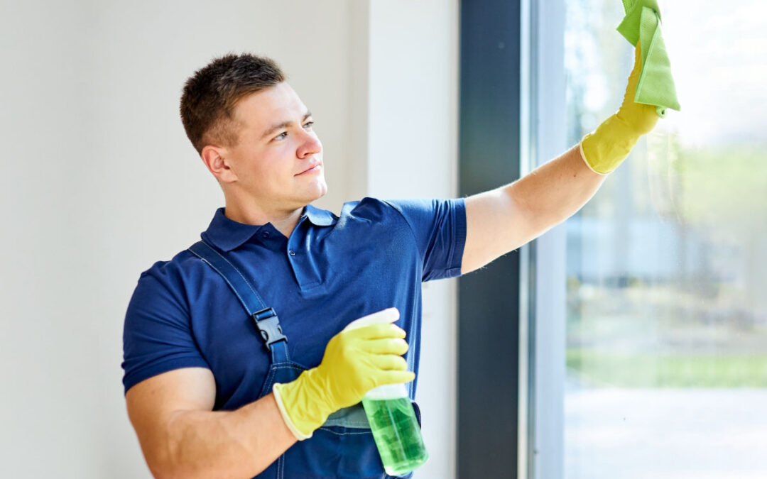 hombre joven limpiando ventanas pvc con producto en una mano y paño suave en otra mano