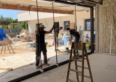 Técnicos instaladores de ventanas colocando hojas de vidrios en chalet de san vicente del raspeig