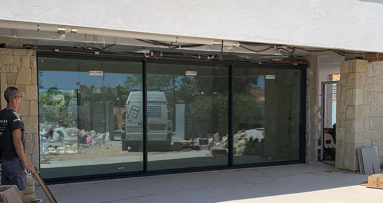 ventanas de aluminio de alta gama vistas desde exterior de un chalet en San Vicente del Raspeig en Alicante. Tiene tres hojas de vidrio deslizante marca guardian sun